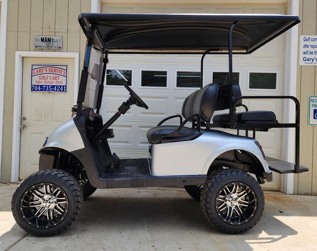 A golf cart is parked in front of a garage.