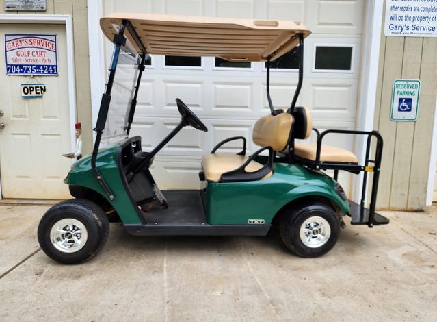 A green golf cart parked in front of a garage.