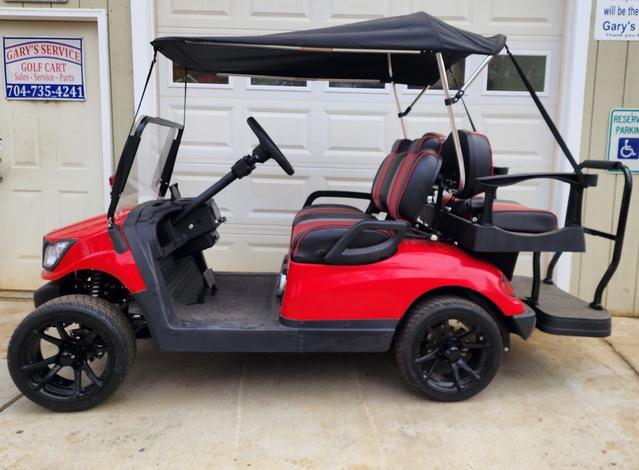 A red golf cart with black seats and wheels.