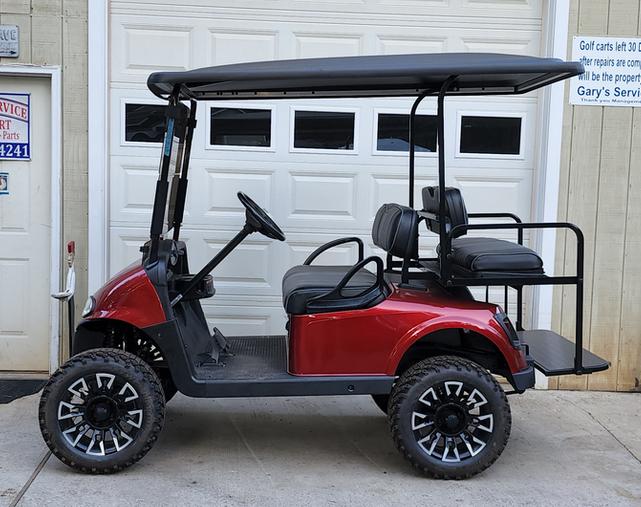 A red golf cart parked in front of a garage.