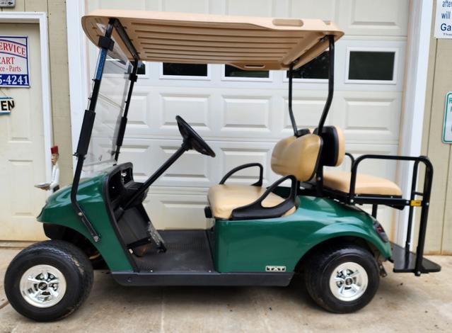 A green golf cart parked in front of a garage door.