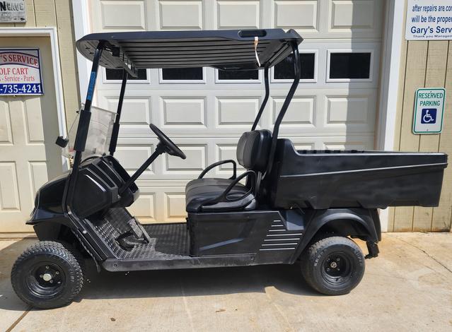 A black golf cart parked in front of a garage door.